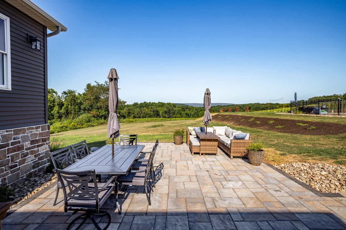Spacious paver patio with dining and seating areas overlooking the landscape in Crossville, TN by Doxa Custom Homes