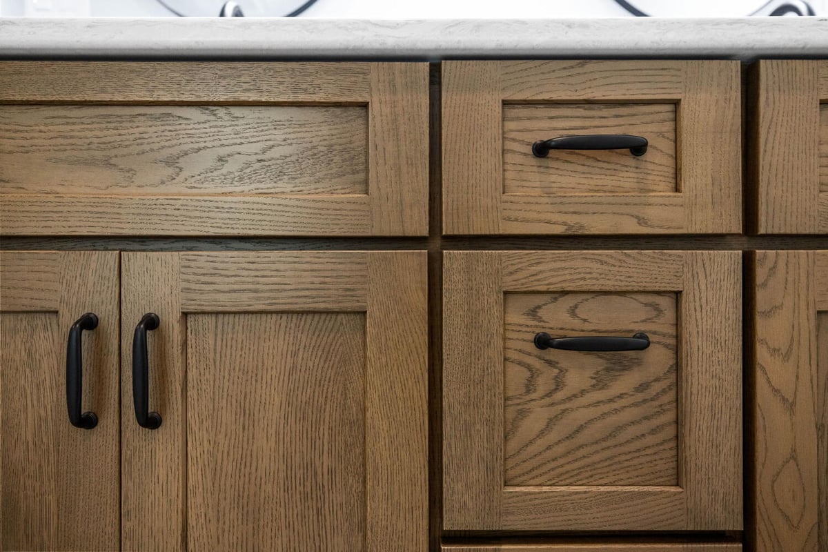 Close-up of natural wood cabinetry with matte black pulls in custom home by Doxa Custom Homes in Crossville, TN
