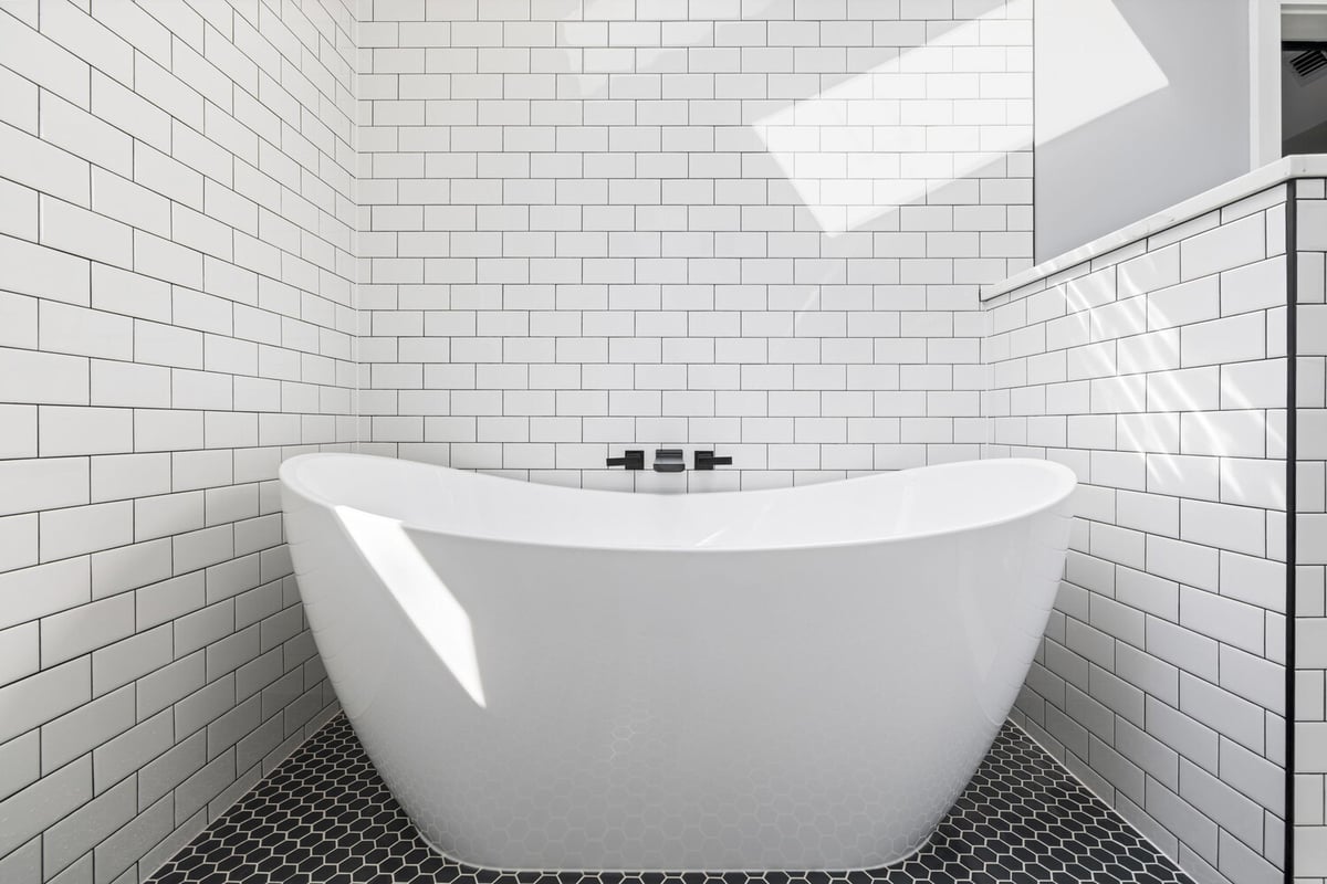 Freestanding bathtub with black tile floor in custom bathroom by Doxa Custom Homes in Murfreesboro, TN