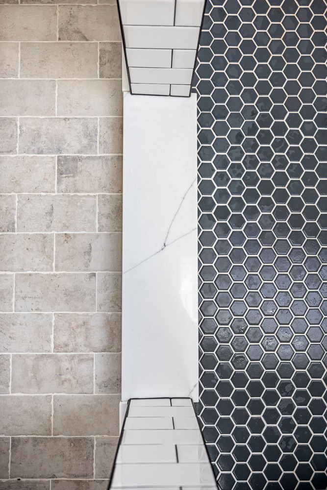Tile transition between brick-style flooring and hexagon shower tile by Doxa Custom Homes in Murfreesboro, TN