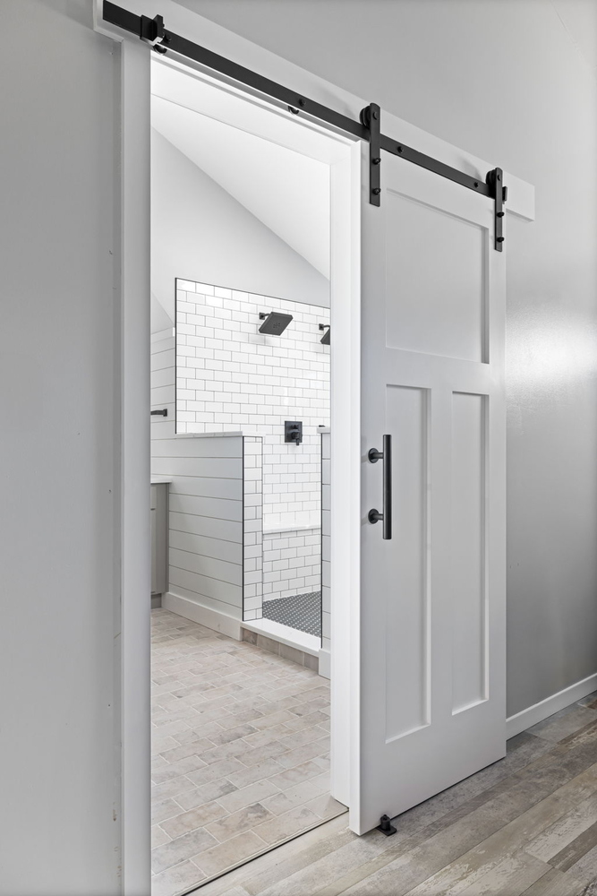 White barn door opening to custom tiled shower by Doxa Custom Homes in Murfreesboro, TN