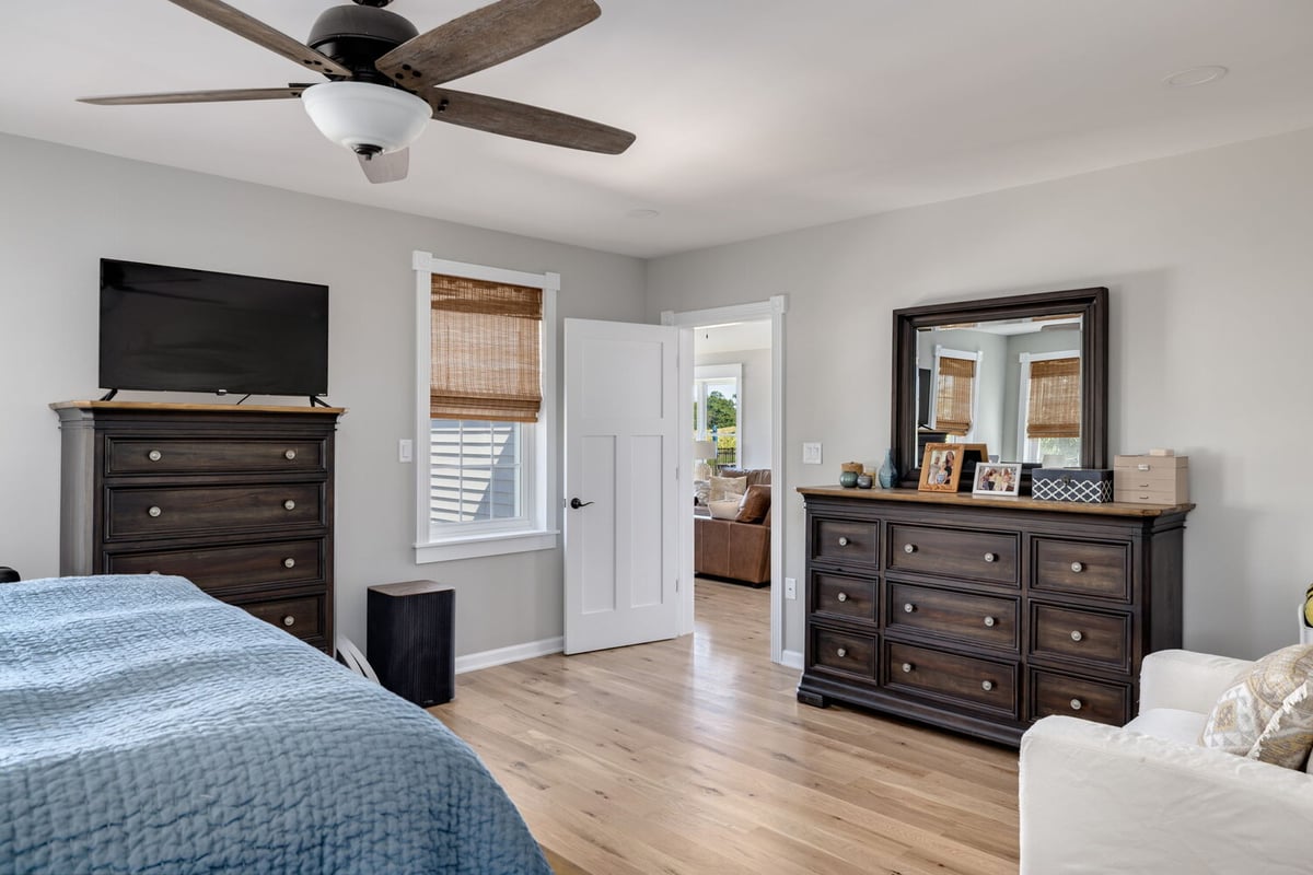 Primary bedroom interior with wood flooring and dark furniture in a custom home by Doxa Custom Homes in Tennessee