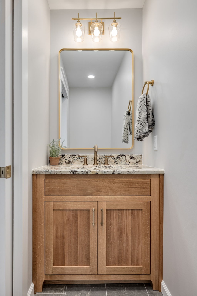 Stylish bathroom vanity with granite and gold accents in Middle Tennessee home by Doxa Custom Homes
