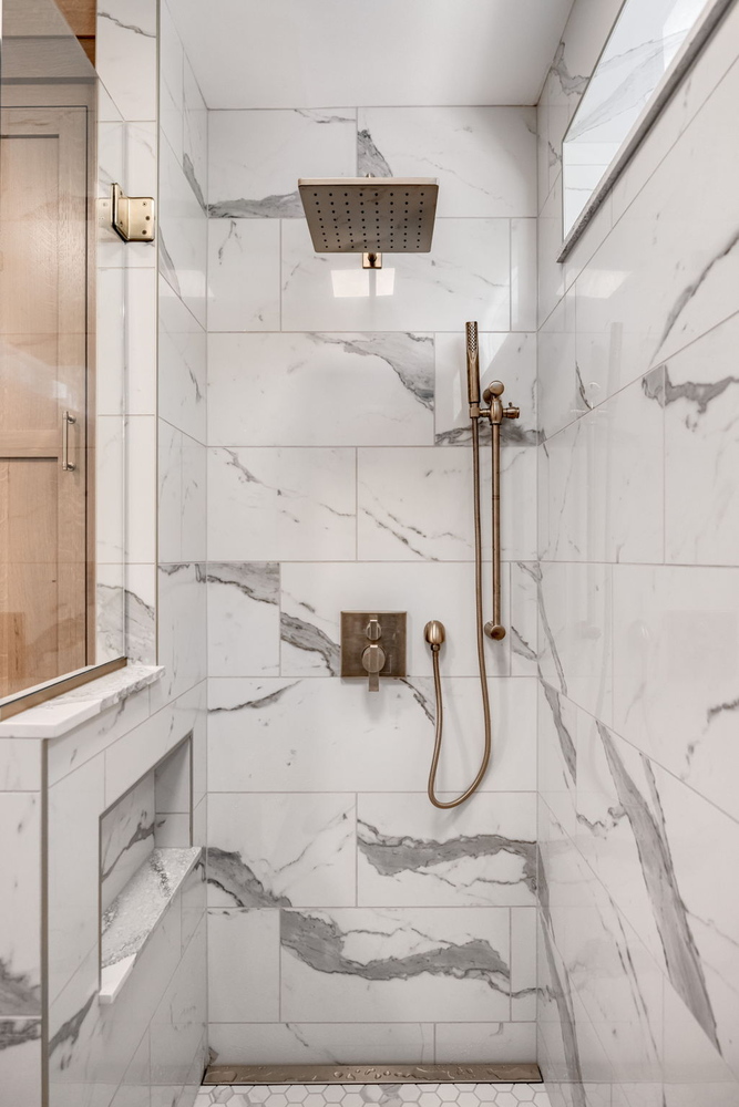 Walk-in shower with marble-look tile and built-in niche in Murfreesboro custom home by Doxa Custom Homes