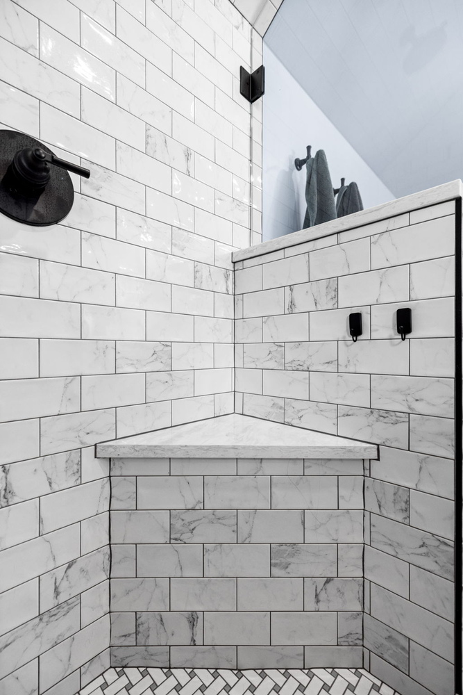 Close-up of marble shower tile and bench in a bathroom remodel by Doxa Custom Homes, Middle Tennessee