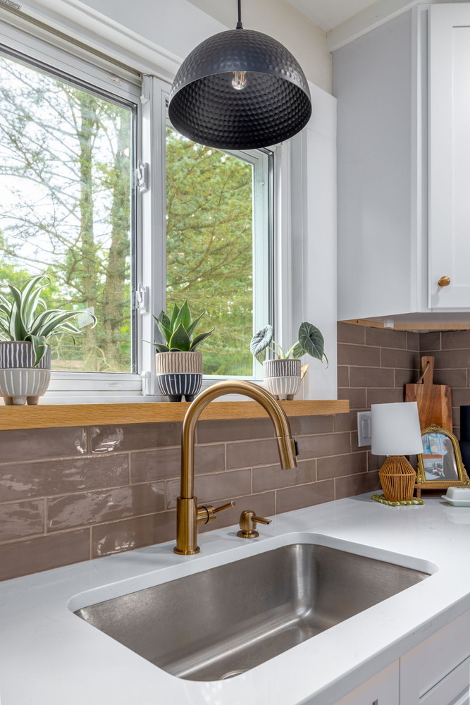 Close-up of kitchen faucet, decor, and brown tile backsplash by Doxa Custom Homes in Cookeville, TN