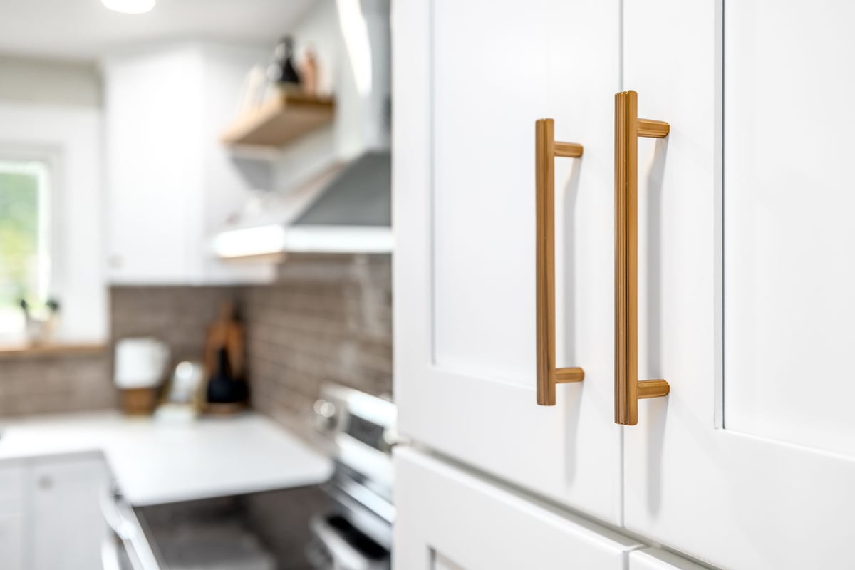 Close-up of modern gold cabinet pulls on white pantry doors by Doxa Custom Homes in Lebanon, TN