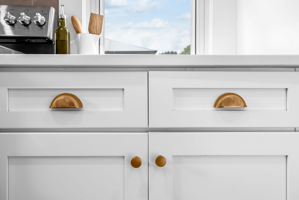 Close-up of white cabinetry with gold half-moon pulls in a custom kitchen by Doxa Custom Homes in Cookeville, TN