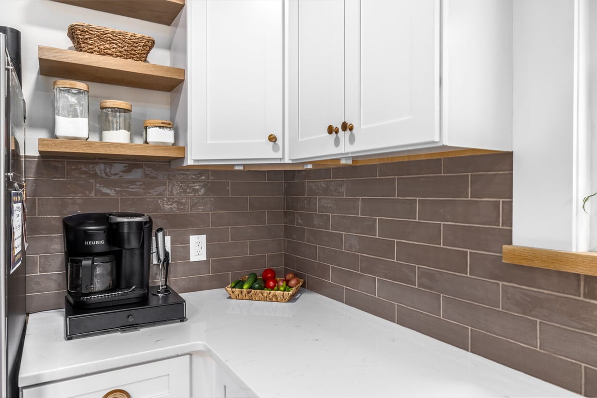 Kitchen corner with white quartz counters and dark subway tile by Doxa Custom Homes in Tennessee