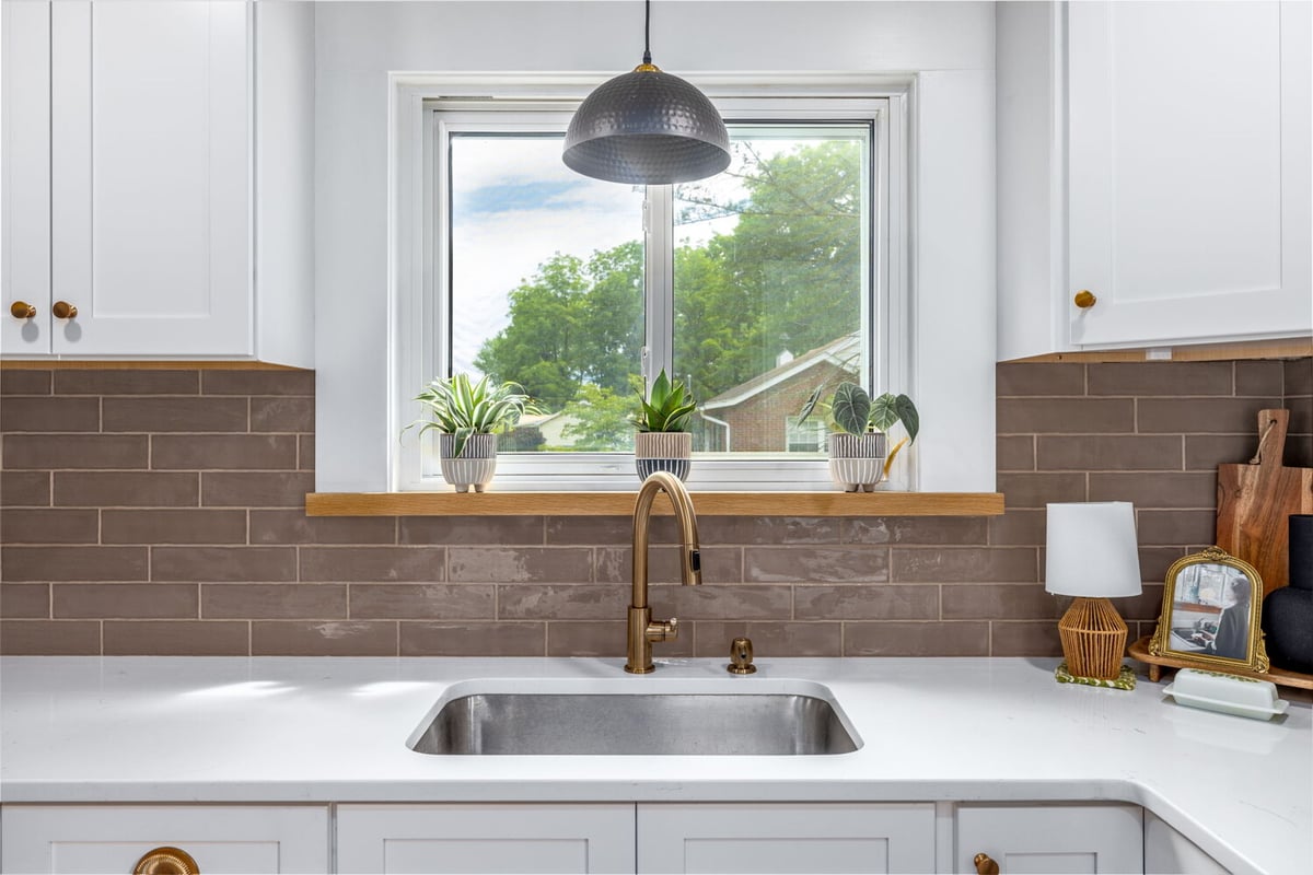 Kitchen sink view with bronze faucet and window plant decor by Doxa Custom Homes in Lebanon, TN