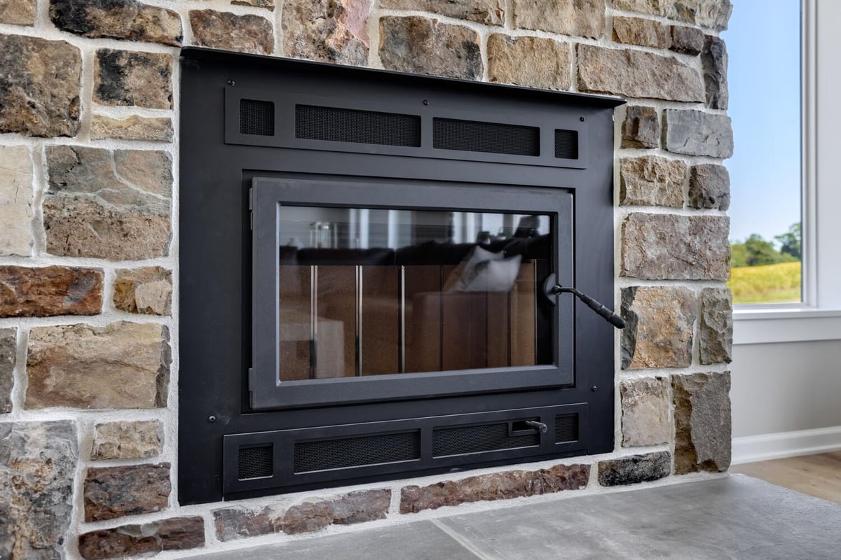 Close-up of built-in stone fireplace with black metal insert in custom home by Doxa Custom Homes in Lebanon, TN