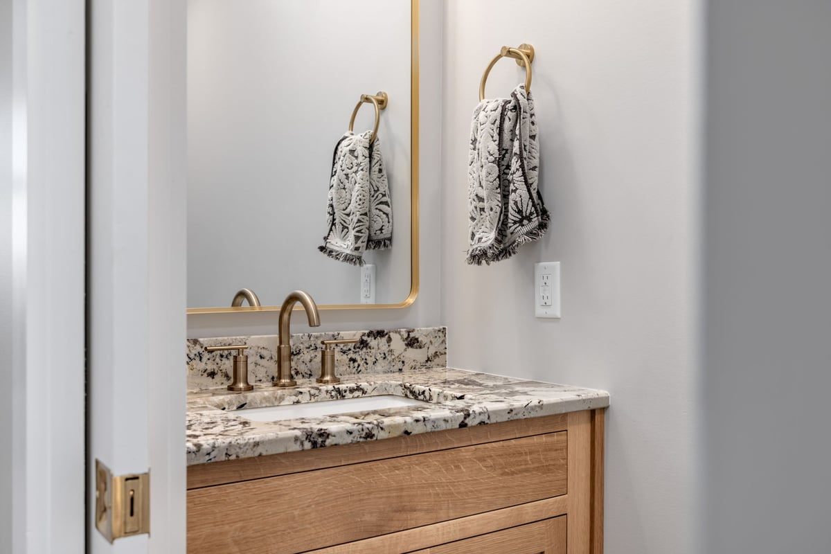 Powder room with granite countertop and brushed gold fixtures in custom home by Doxa Custom Homes in Lebanon, TN