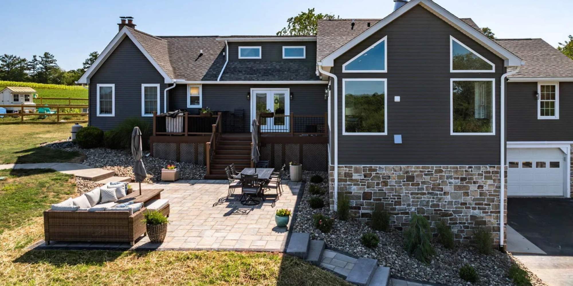 Dark exterior custom home with large windows and stone veneer base by Doxa Custom Homes