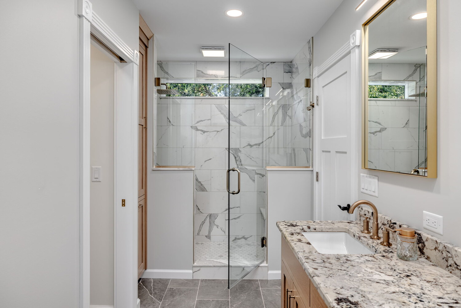 Marble tile shower with frameless glass door in custom bathroom by Doxa Custom Homes in Cookeville, TN