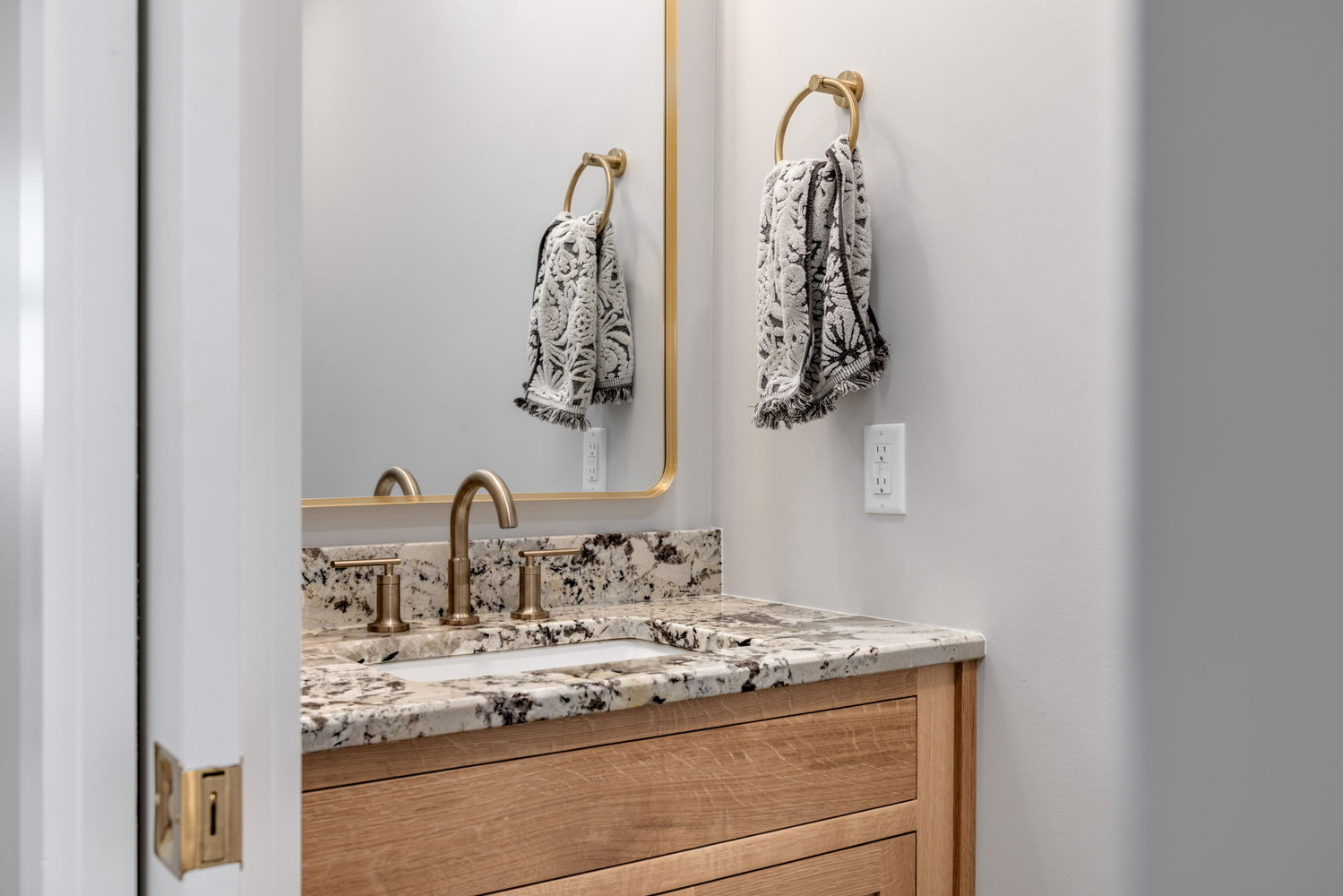 Powder room with granite countertop and brushed gold fixtures in custom home by Doxa Custom Homes in Lebanon, TN