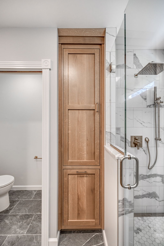 Vertical wood storage cabinet and tiled shower in luxury bathroom by Doxa Custom Homes in Tennessee